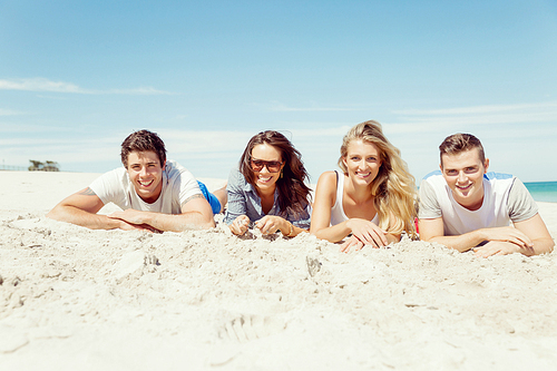 Company of young friends on the beach relaxing on white sand
