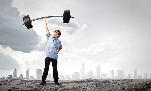 Cute boy of school age lifting barbell above head