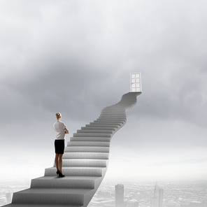 Businesswoman walking up staircase to door in sky