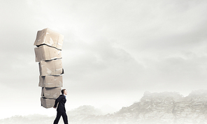 Businessman carrying big stack of carton boxes