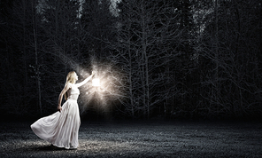 Young woman with lantern walking in dark forest