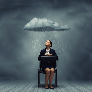 Young upset businesswoman with suitcase sitting on chair