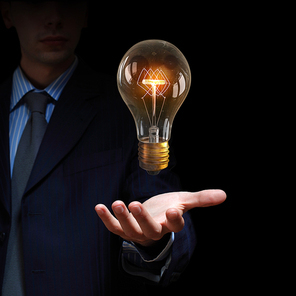 Businessman presenting glass glowing light bulb in his hand