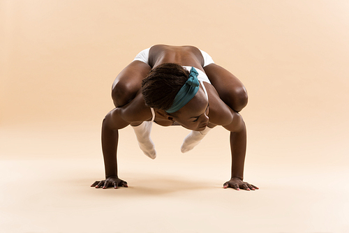 Young African woman doing yoga in stretching position