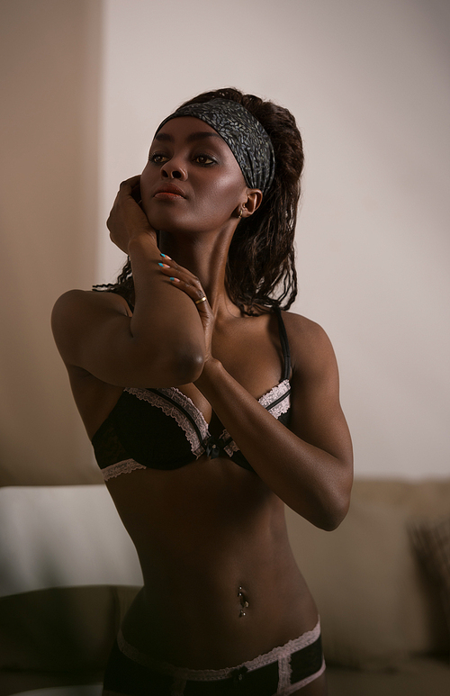 Beautiful alluring african woman in sexy lingerie. Portrait of beautiful sexy stylish young woman model with perfect clean skin in black lingerie posing on chair