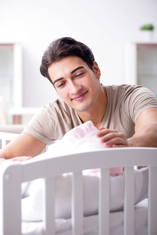 Young father enjoying time with newborn baby at home