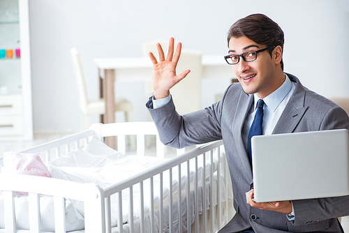 Young businessman trying to work from home caring after newborn baby