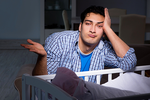 Young father dad sleeping while looking after newborn baby