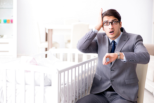 Young businessman trying to work from home caring after newborn baby