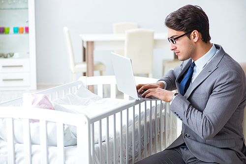 Young businessman trying to work from home caring after newborn baby