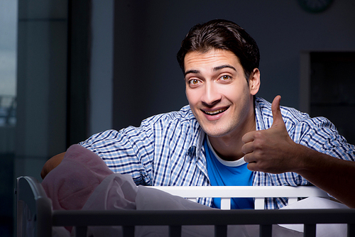 Happy dad looking after newborn baby at night