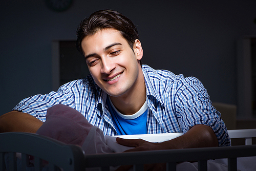 Happy dad looking after newborn baby at night