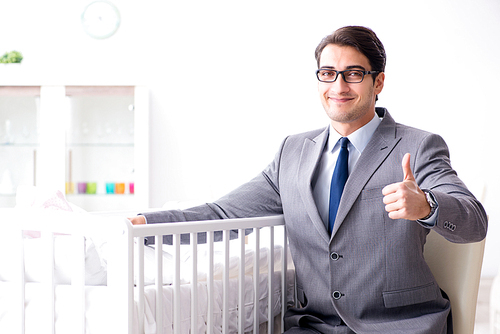 Young businessman trying to work from home caring after newborn baby