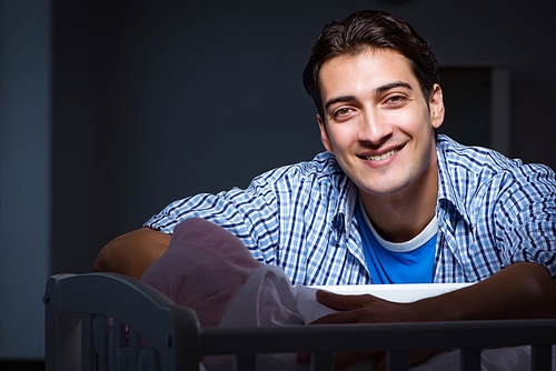 Happy dad looking after newborn baby at night