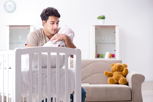 Young father enjoying time with newborn baby at home