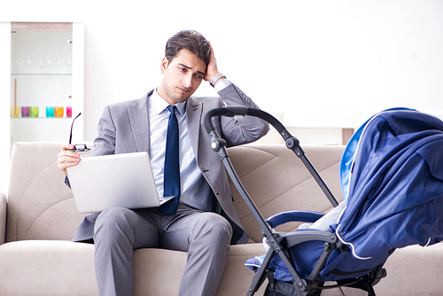 Businessman looking after newborn baby at home and teleworking