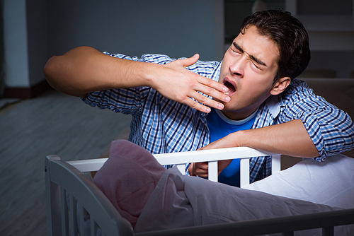 Young father dad sleeping while looking after newborn baby