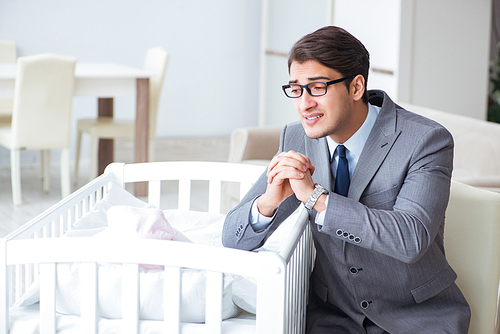 Young businessman trying to work from home caring after newborn baby