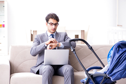 Businessman looking after newborn baby at home and teleworking