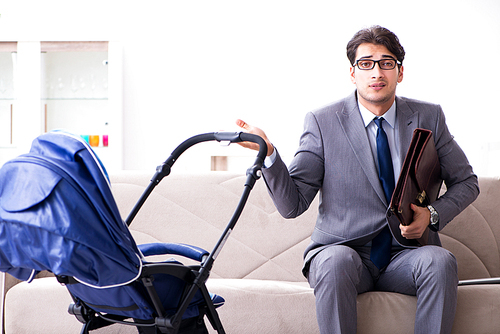 Businessman looking after newborn baby at home and teleworking