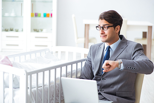 Young businessman trying to work from home caring after newborn baby