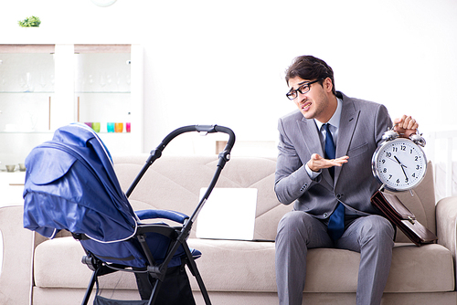 Businessman looking after newborn baby at home and teleworking