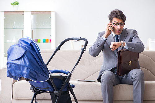 Businessman looking after newborn baby at home and teleworking