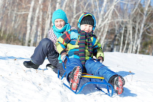 Boy and girl enjoying sledge ride in beautiful snowy winter park