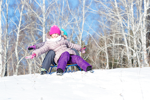 Two cute girls enjoying sledge ride in beautiful snowy winter park