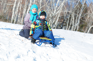 Boy and girl enjoying sledge ride in beautiful snowy winter park