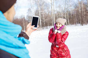 Young man in winter park making photo of his girlfriend