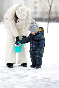 Winter portrait of toddler boy with mother in warm coat outdoors