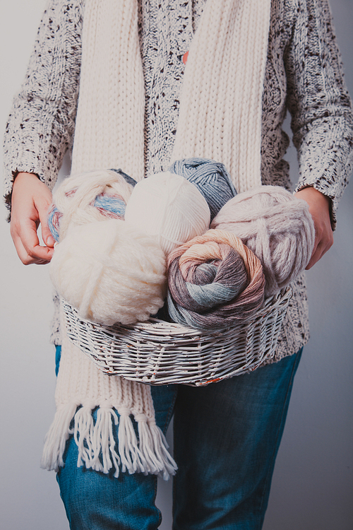 Warmly dressed woman holding a basket of balls of woolen yarn