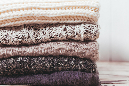 Stack warm knitted sweaters in white and gray shades
