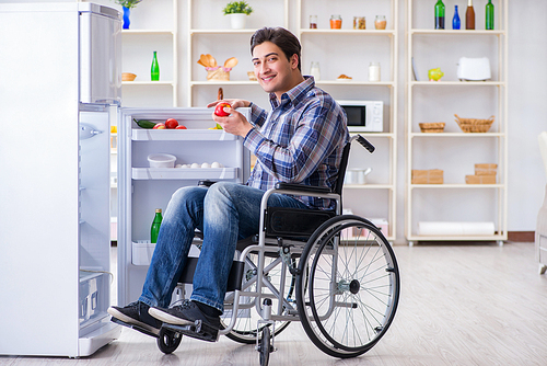 Young disabled injured man opening the fridge door