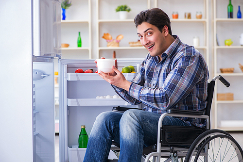 Young disabled injured man opening the fridge door