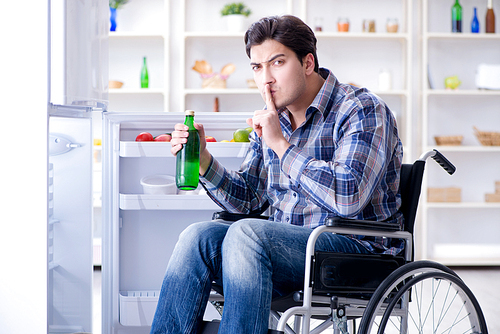 Young disabled injured man opening the fridge door