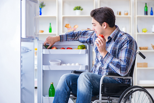 Young disabled injured man opening the fridge door