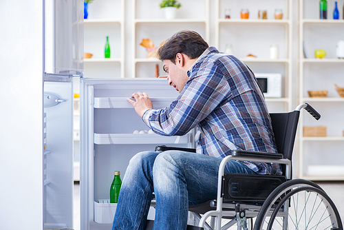 Young disabled injured man opening the fridge door