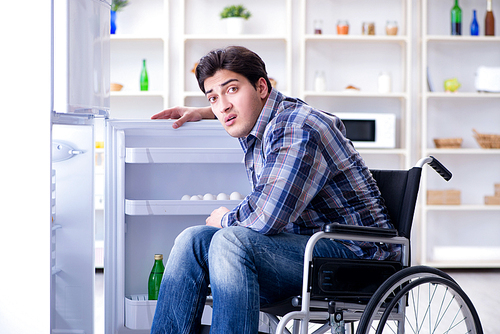 Young disabled injured man opening the fridge door