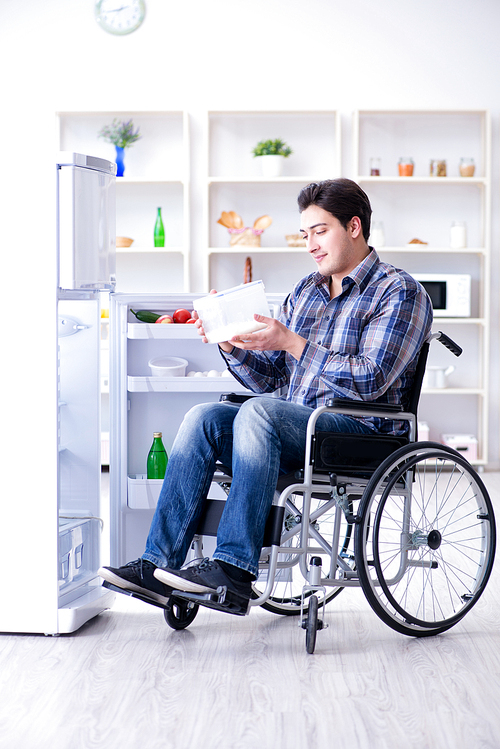 Young disabled injured man opening the fridge door