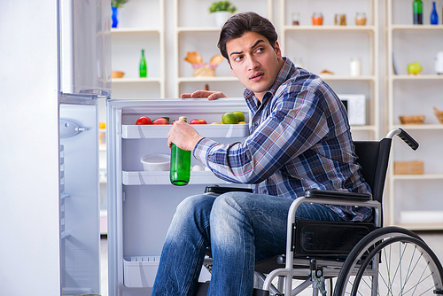 Young disabled injured man opening the fridge door