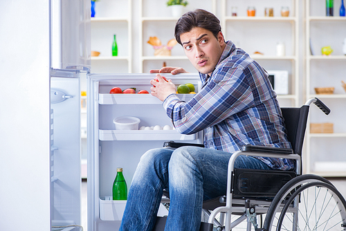 Young disabled injured man opening the fridge door