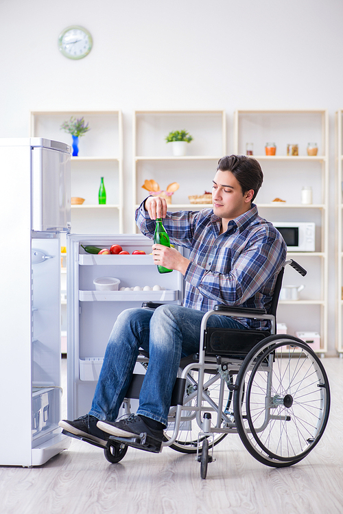 Young disabled injured man opening the fridge door