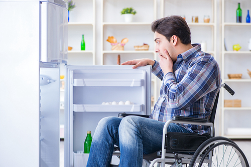 Young disabled injured man opening the fridge door