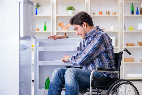 Young disabled injured man opening the fridge door