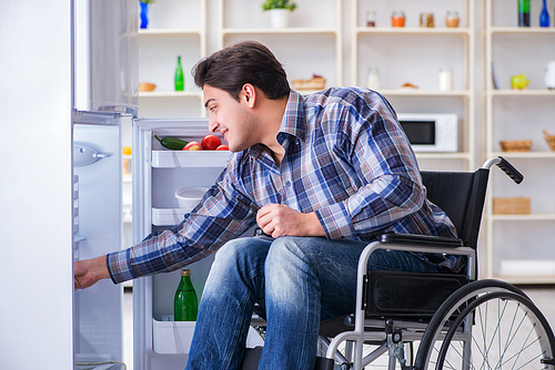 Young disabled injured man opening the fridge door