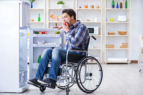 Young disabled injured man opening the fridge door