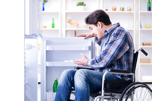 Young disabled injured man opening the fridge door