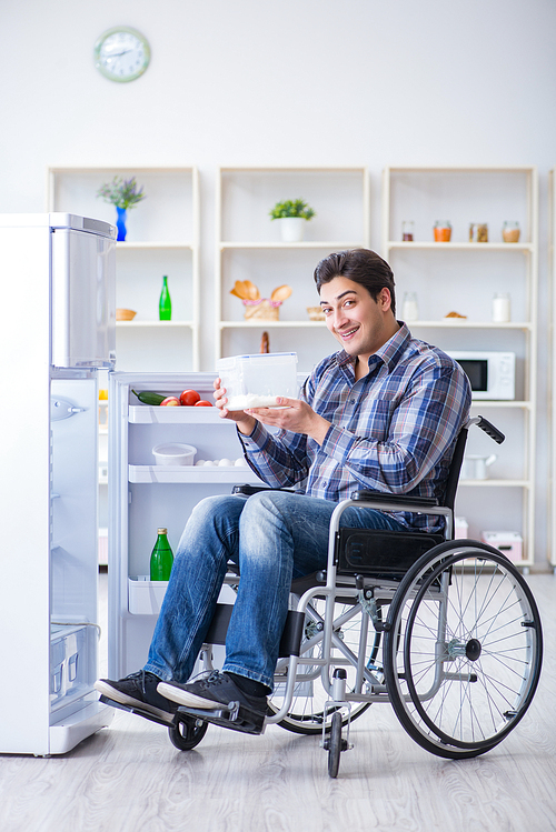 Young disabled injured man opening the fridge door